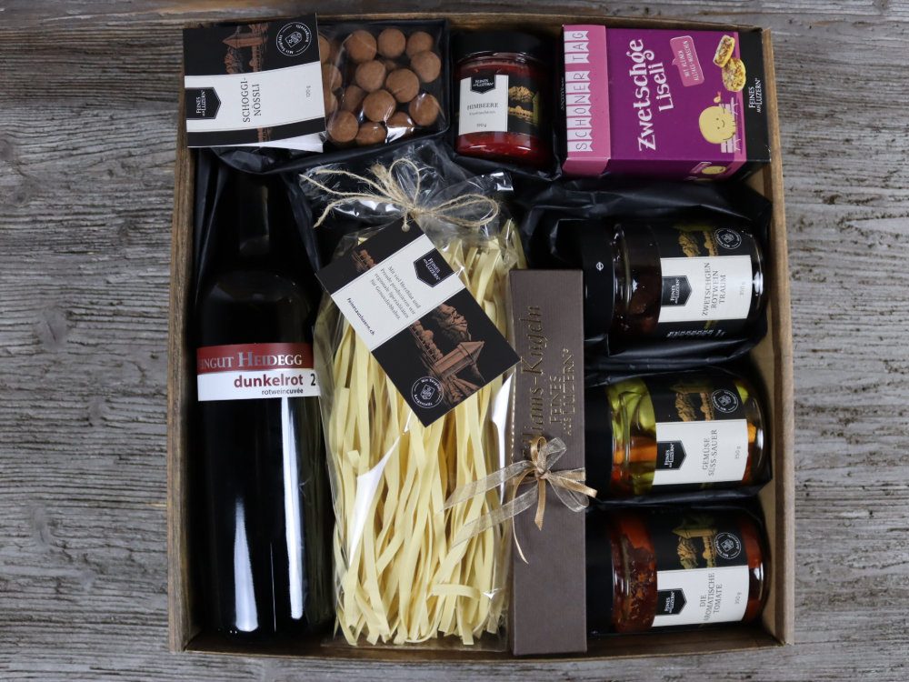 Eine wunderbar kulinarische Geschenk-Box mit feinen Köstlichkeiten. Eierteigwaren, aromatische Tomate, Süss-saures Gemüse, Zwetschgen-Rotwein-Traum, ein Wein vom Weingut Heidegg, Zwetschgenliseli, Schogginössli, 6er Williamskugeln, Fruchtaufstrich Himbere und eine schön dekorierte Geschenkbox