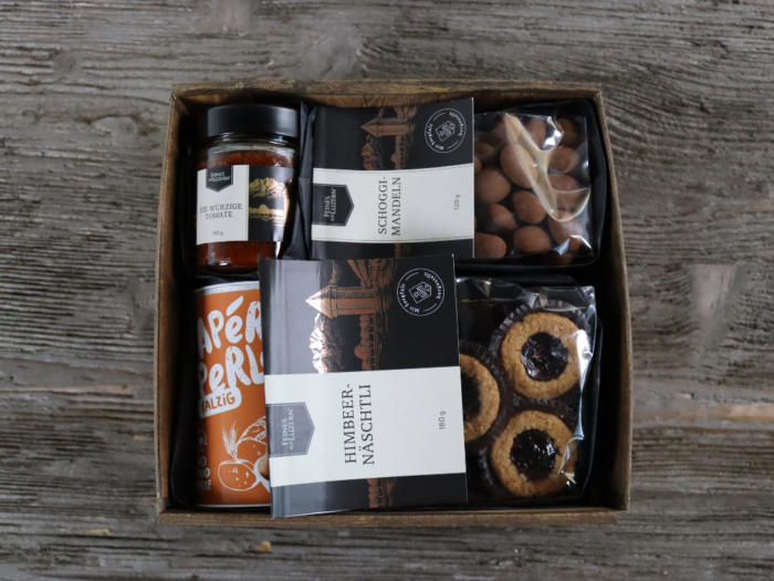 Was für eine Überraschung! Diese Geschenk-Box ist wunderbar gefüllt mit süssen und salzigen Köstlichkeiten. HImbeernäschtli, Schogginössli, Apéro Perlen, würzige Tomate verpackt in einer Geschenkbox mit saisonaler Deko.